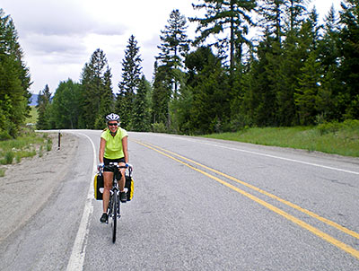 Woman riding bicycle through forest